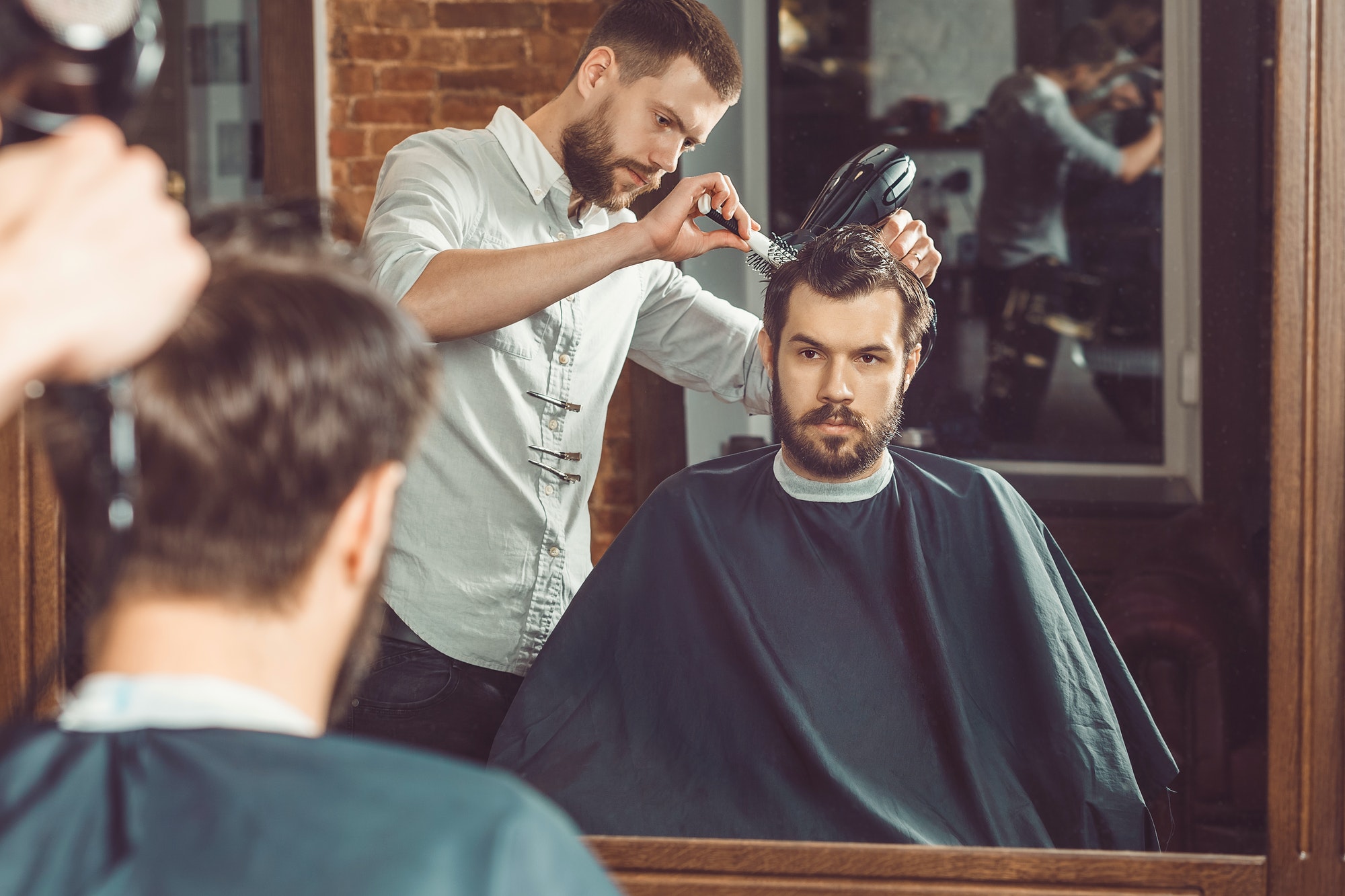 young-handsome-barber-making-haircut-of-attractive-man-in-barbershop.jpg